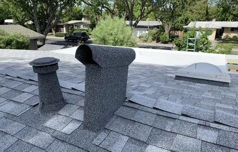 Stone coated dormer vent on a light grey roof above a neighborhood