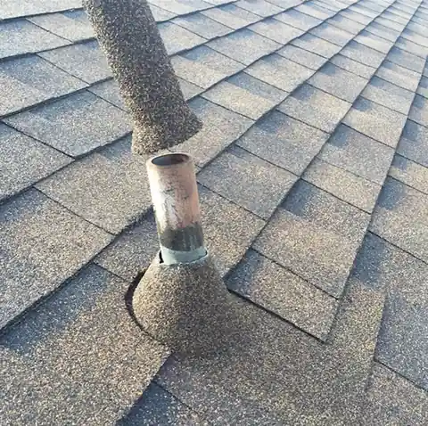 A stone coated sleeve sliding down over an existing pipe on a shingle roof